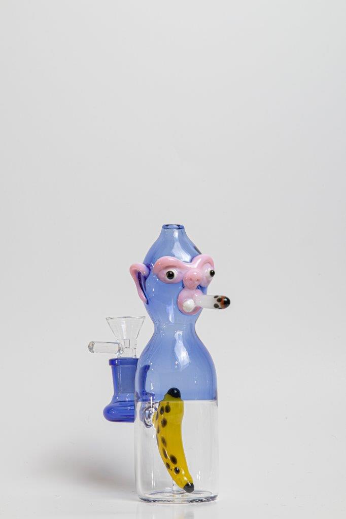 7 inch Smoking Monkey Water Pipe – a whimsical addition to your weed and dab collection in water bong style glass. For sale now, this unique water bottle-shaped piece includes a 14MM male bowl and a banana-shaped bent down stem. The integrated percolator ensures a smooth smoking experience, preventing water splashback, cooling the smoke down, and providing extra filtration